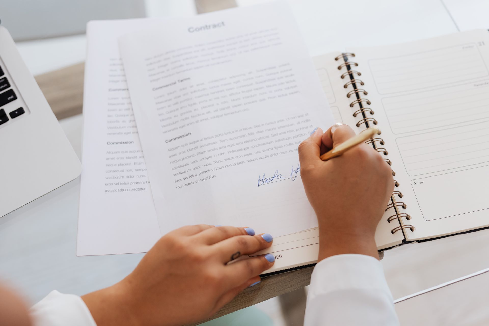 Hands signing a printed contract on a desk