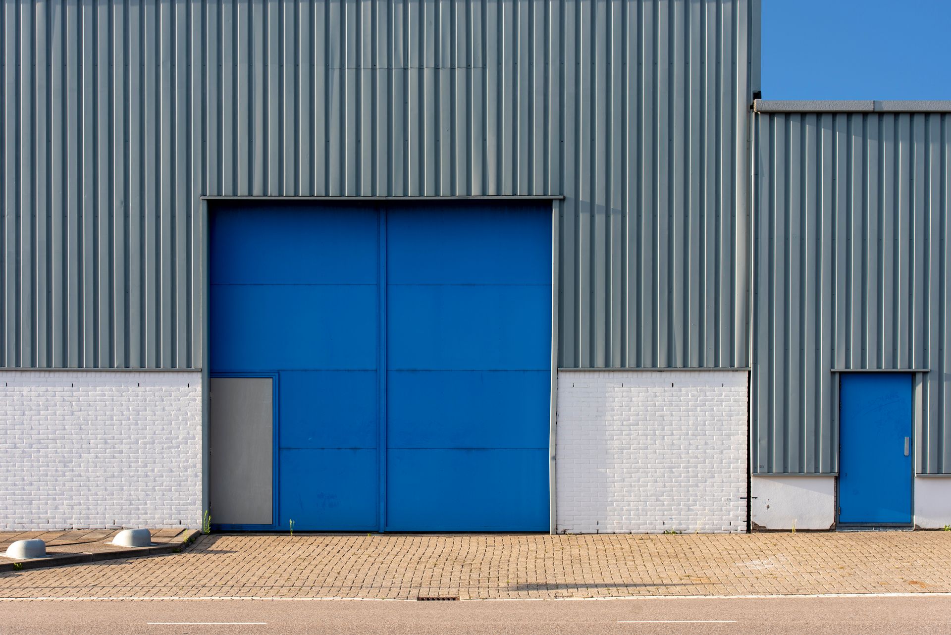 Grey metal warehouse exterior with large blue loading doors
